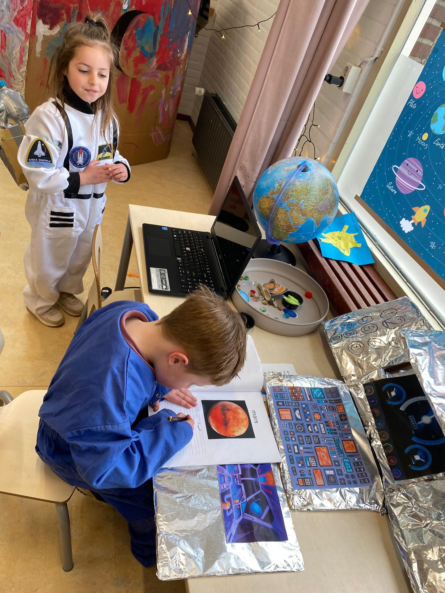 De afgelopen weken hebben we binnen onderwijsteam C (groepen 1-2-3) op locatie de Essen gewerkt binnen het thema: ‘als ik een astronaut ben, dan...’
Stap voor stap hebben we het heelal verkend, te beginnen bij onze eigen planeet aarde. We vroegen ons af waarom we de aarde eigenlijk de blauwe planeet noemen en ontdekten hoe het komt dat het dag en nacht wordt. Nieuwsgierige vragen van de kinderen brachten ons verder: ‘als de aarde rond is, waarom vallen we er dan niet af?’🌎
Van daaruit reisden we verder langs de zon, de maan en de sterren.🌞🌙✨
We leerden over sterrenbeelden, kometen en meteoren en maakten kennis met het zonnestelsel en al zijn planeten. Ook doken de kinderen in de rol van astronaut of sterrenkundige in de themahoek waardoor het spel tot leven kwam.
Vandaag sloten we dit bijzondere thema af met kijkochtend voor ouders. Elke groep gaf daar op zijn eigen manier vorm aan: met een liedje, een versje of een presentatie. Wat hebben we genoten van alle optredens en van het enthousiasme van de kinderen! De betrokkenheid was groot en het was prachtig om te zien hoeveel ze hebben geleerd. Een reis om trots op te zijn 🚀